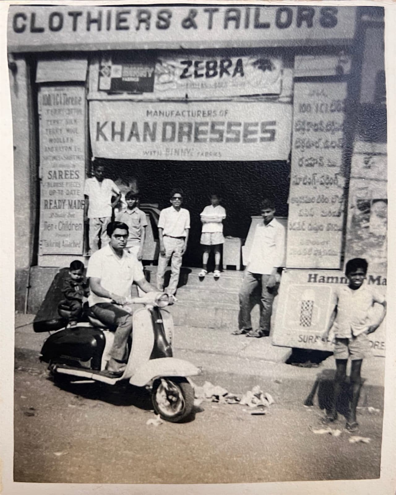 Chairman Ahmed Ali Khan on Scooter at Khan Dresses (1960) (Circa 1960) - A rare 1960 archival capture of Chairman Mohammed Ahmed Ali Khan on his scooter outside the historic "Clothiers & Tailors - Khan Dresses" storefront. | MF.Khan Heritage Archives Visakhapatnam