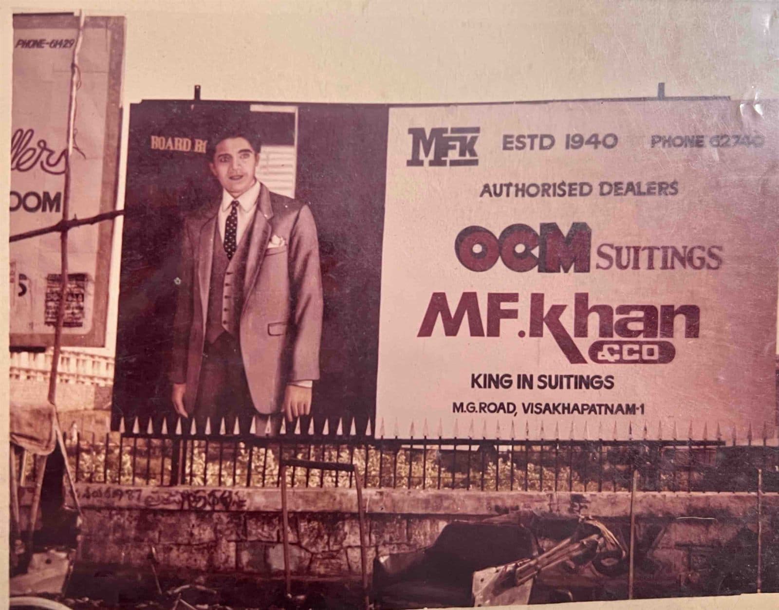Historic Billboard: MF.Khan — "King in Suitings" (1980s) - Iconic 1980s roadside billboard on M.G. Road featuring the slogan "King in Suitings", highlighting MF.Khan as authorized dealer for OCM Suitings (Phone 62740). | MF.Khan Heritage Archives Visakhapatnam