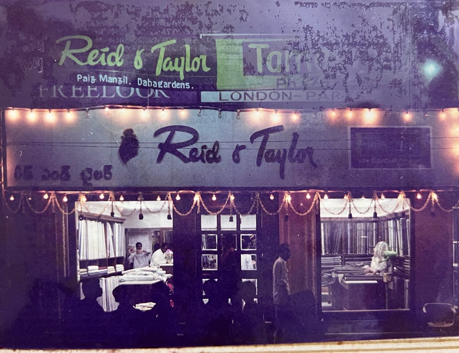 Reid & Taylor Flagship Storefront Decorated for Opening (2000s) - The illuminated Reid & Taylor and Freelook luxury flagship storefront adorned with celebratory evening lights and garlands on its grand opening night. | MF.Khan Heritage Archives Visakhapatnam